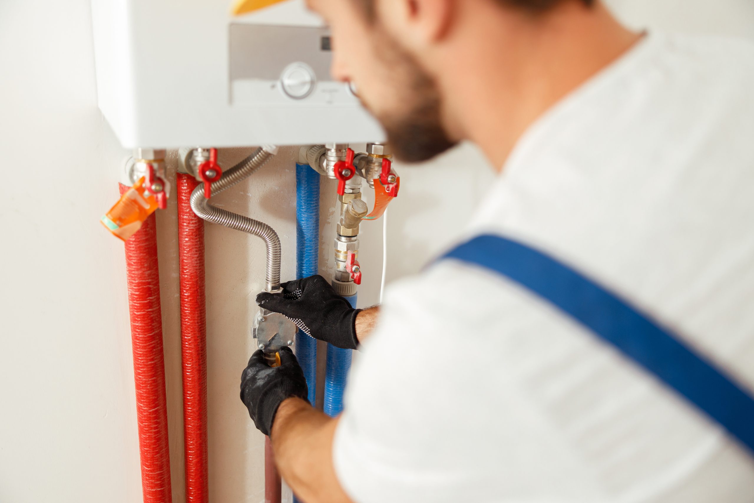 Closeup of plumber working with water pipes while installing heating system in apartment